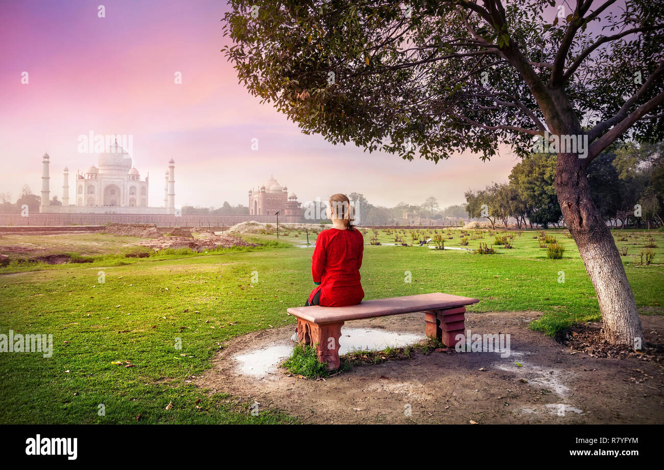 Frau in Rot auf der Bank sitzen in Mehtab Bagh und im Taj Mahal in Agra, Uttar Pradesh, Indien Stockfoto