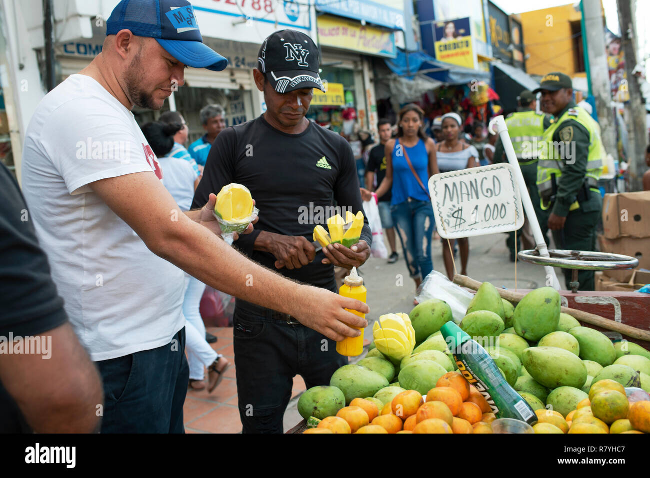 Latino Obst Anbieter schneiden Mango (mit pikanter Sauce und Salz) an Bazurto Markt (Mercado Bazurto) in Cartagena de Indias, Kolumbien. Okt 2018 Stockfoto