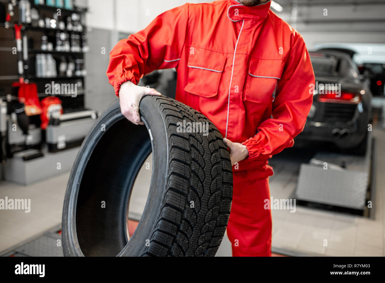 Arbeiter in Uniform tragen neue Reifen am Auto Service oder Store, Nahaufnahme Stockfoto