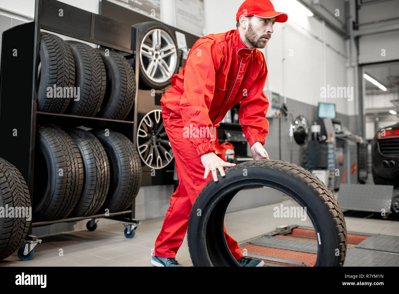 Auto service Arbeitnehmer in roter Uniform tragen neue Reifen auf den Reifen Montage Service oder Shop Stockfoto