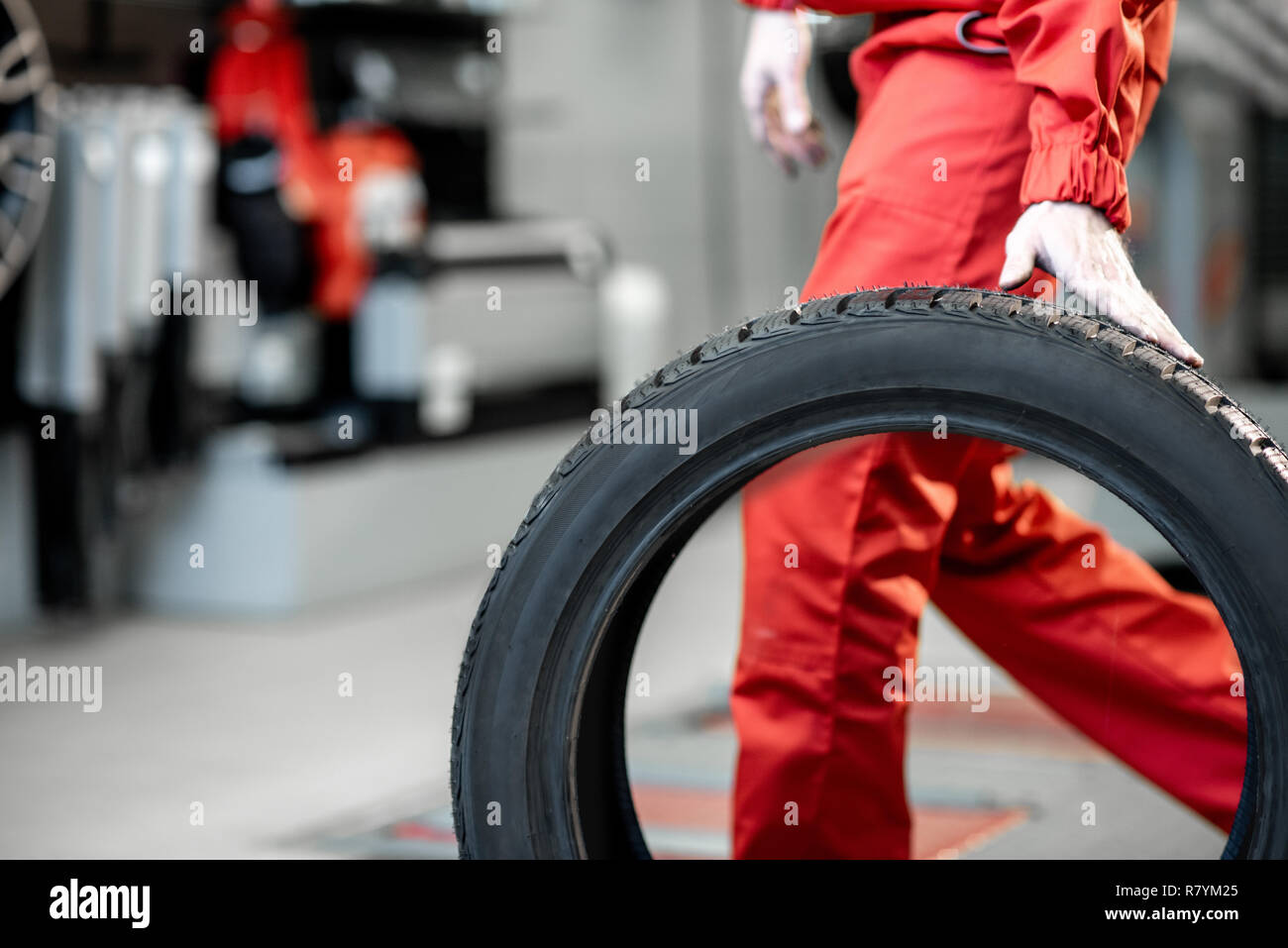Arbeiter in Uniform tragen neue Reifen am Auto Service oder Store, Nahaufnahme Stockfoto