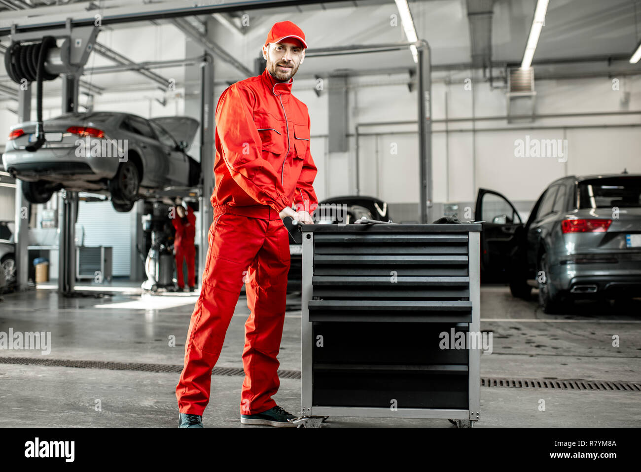 Zwei Automechaniker in roter Uniform gehen mit der Karre am Auto Service Stockfoto