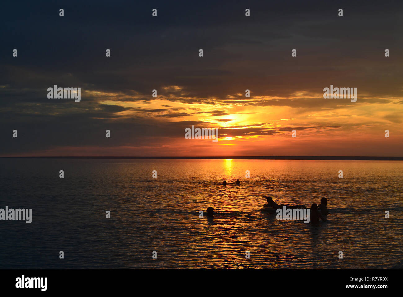 Eine Gruppe von Menschen schwimmen in ruhigem Wasser in das Licht der brennenden Sonne. Stockfoto