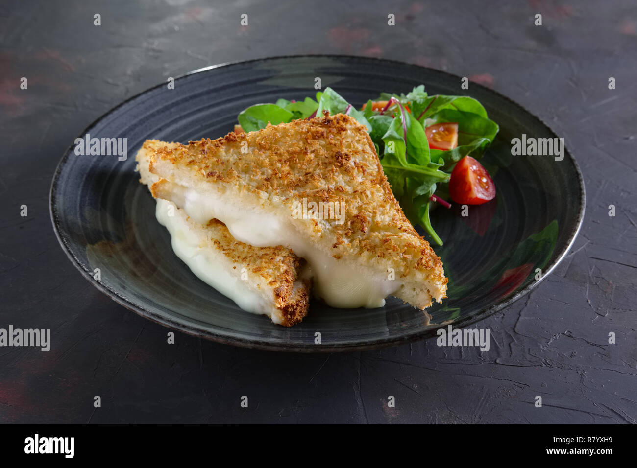 Club Sandwich mit geschmolzenem Käse innen serviert mit Cherry Tomaten und Salat Stockfoto