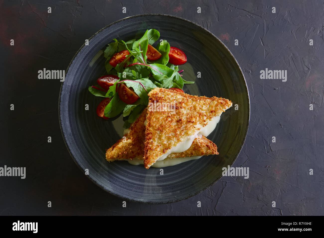 Club Sandwich mit geschmolzenem Käse innen serviert mit Cherry Tomaten und Salat Stockfoto