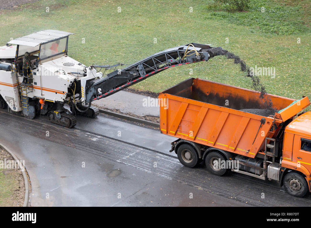 Straßenfräse entfernt alte Asphalt und Lasten Asphalt in die Dump Truck gefräst. Straße Reparatur. Hohe Betrachtungswinkel Stockfoto