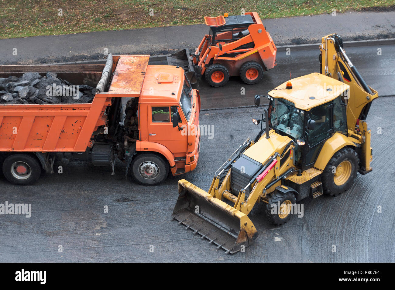 Große jackhammer und Rad mini bagger entfernt alte Asphalt und lädt sie in die Dump Truck. Straßenbau arbeiten. Straße Erneuerung Stockfoto