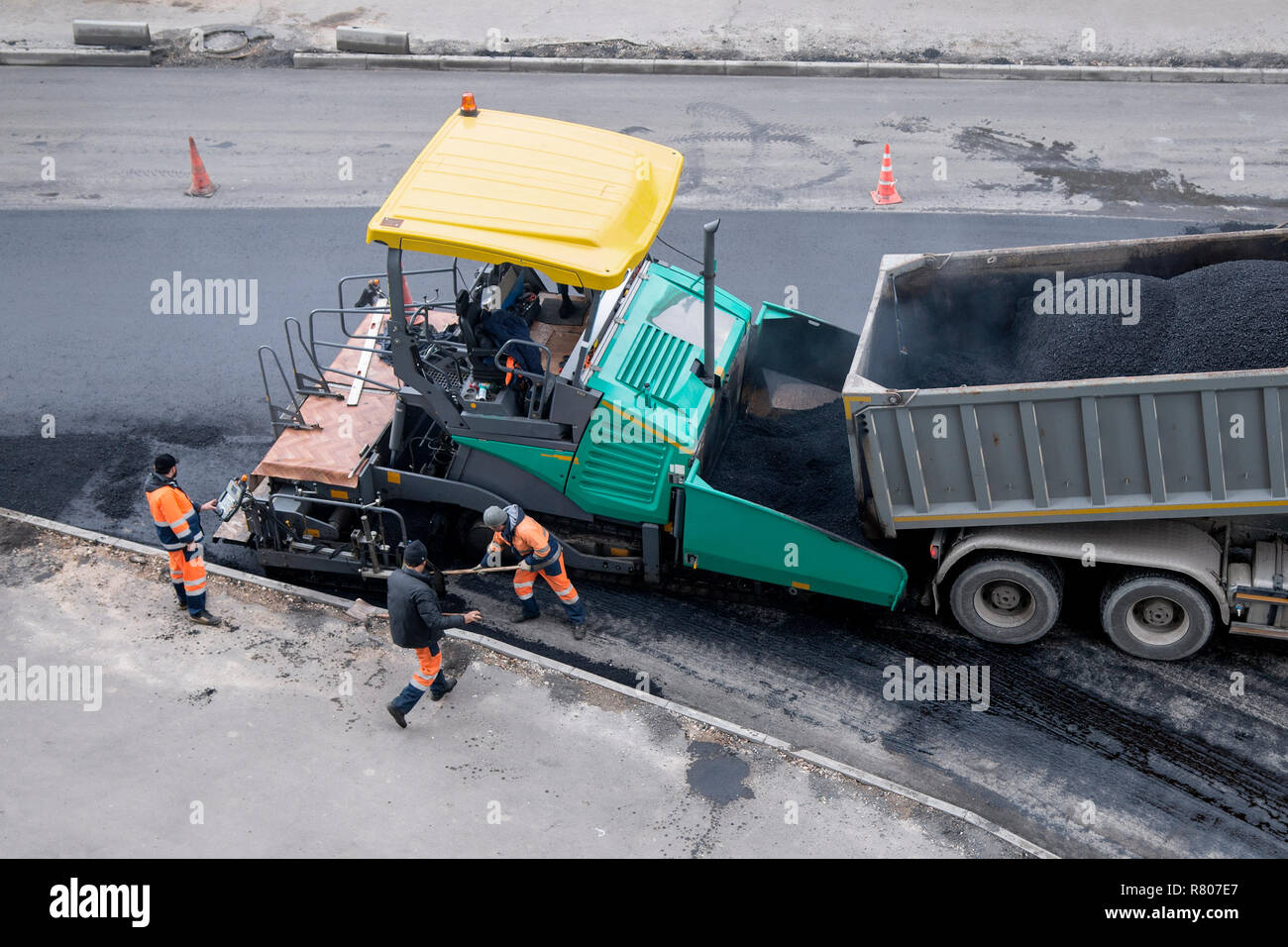 Ein Pflasterstein Maschine oder fertiger Finisher Orte eine Schicht von frischem Asphalt. Nicht erkennbare Arbeitnehmer. Straßenbau arbeiten, Erneuerung Stockfoto