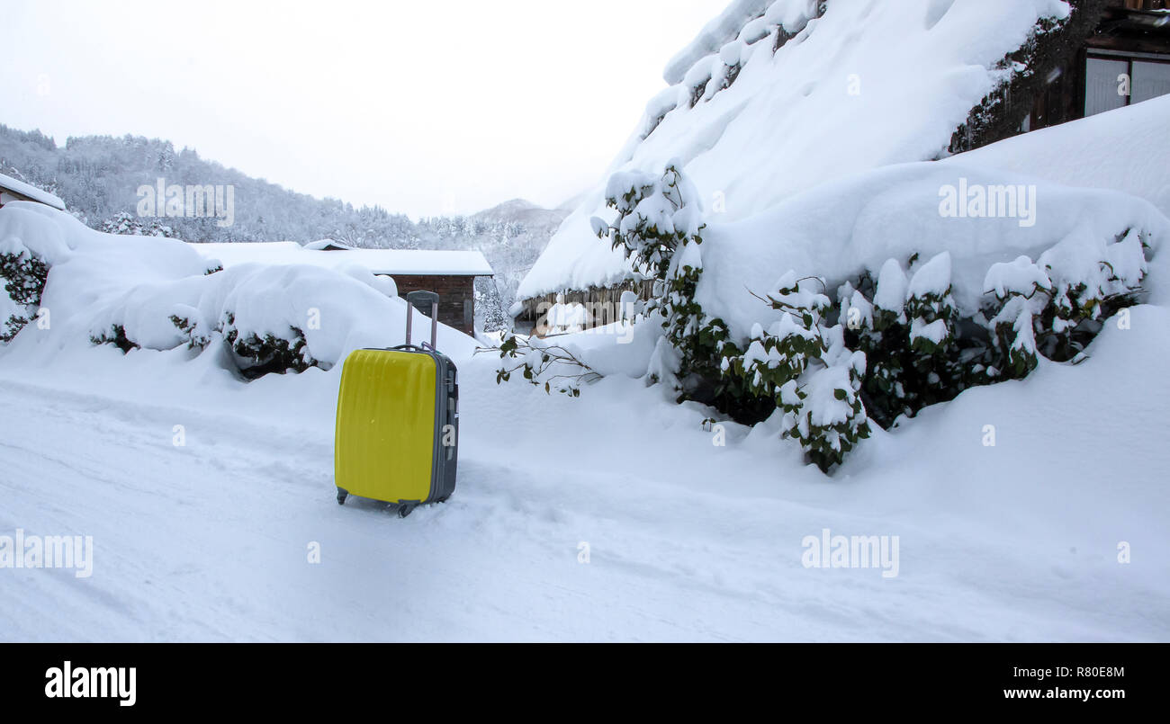 Gelbe Gepäck auf der Straße mit Schnee im Hintergrund. Stockfoto