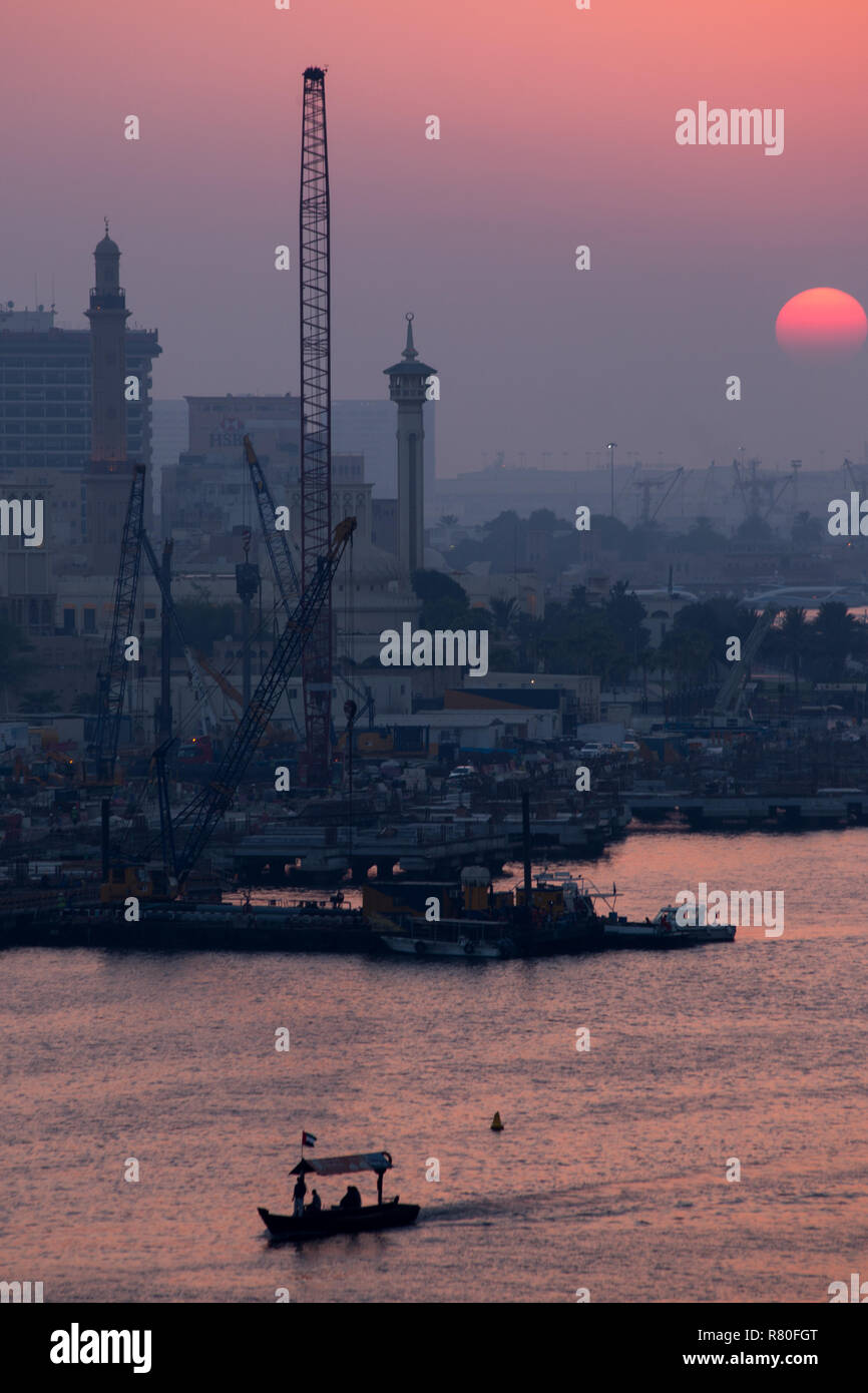 Abras segeln bei Sonnenuntergang auf dem Dubai Creek in den Vereinigten Arabischen Emiraten. Stockfoto