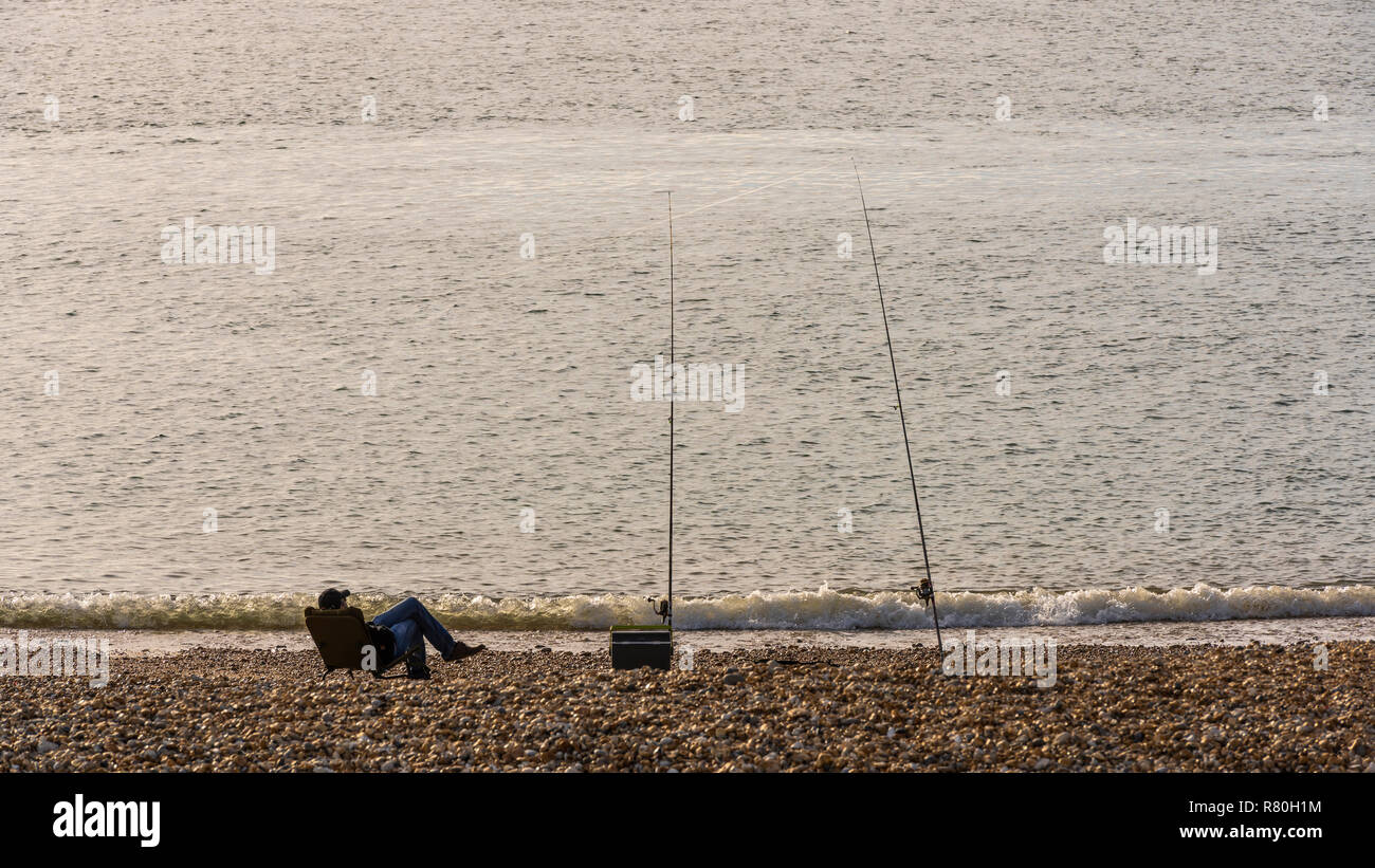 Keyhaven, England - Oktober 24, 2018: Angler mit zwei Angeln am Strand in den Sand am Ufer des Meeres sitzen., England. Stockfoto