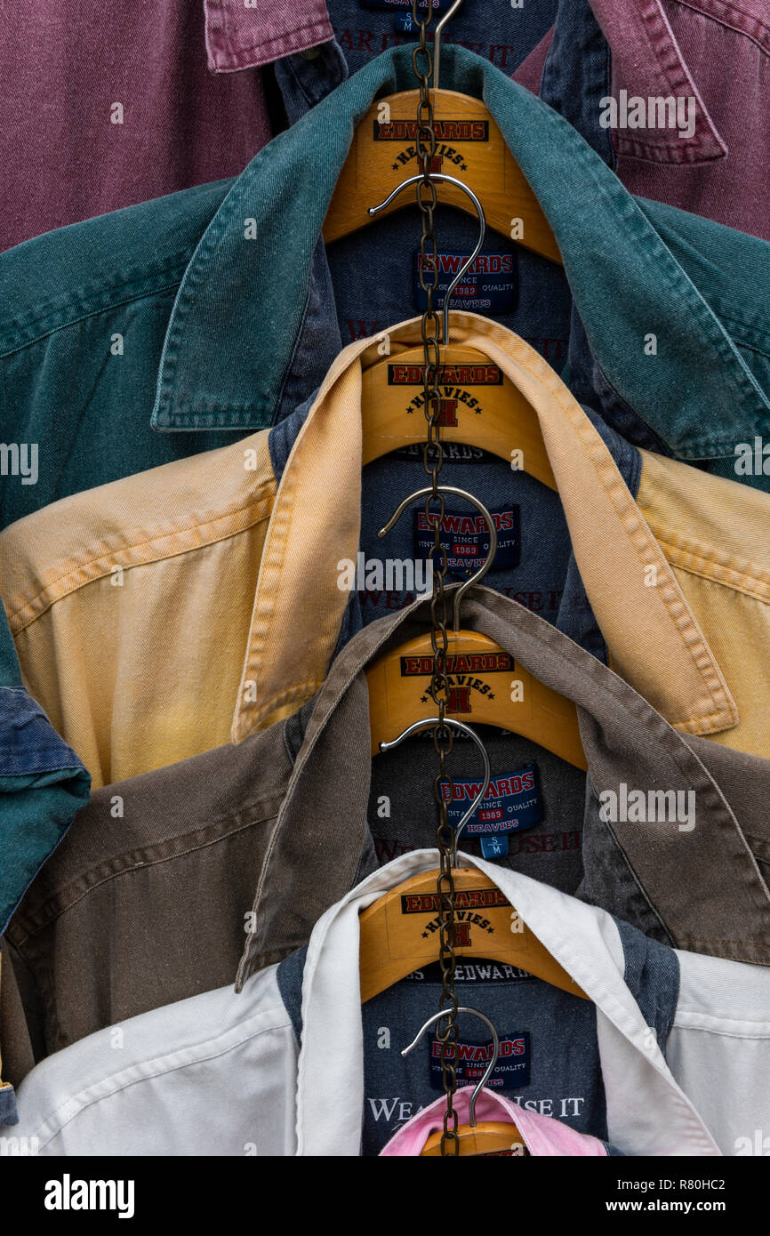 Lymington, England - Oktober 25, 2018: Verschiedene Shirts und Farben hängen an Kleiderhaken in einem Geschäft. Stockfoto