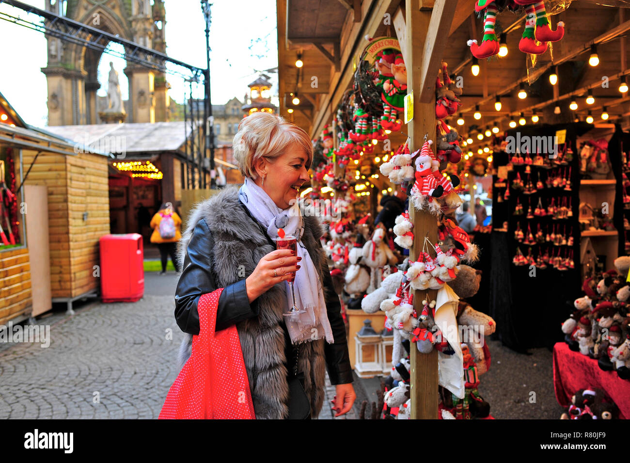 Frau mittleren Alters halten Trinken suchen an Weihnachten Geschenk auf Manchester Weihnachtsmarkt in Albert Square 2018 Abschaltdruck Stockfoto