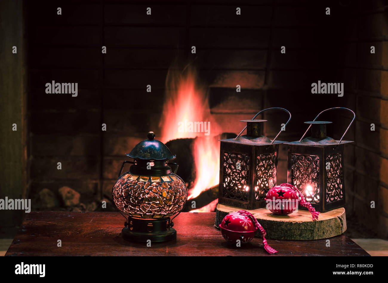 Weihnachten Komposition mit Laternen und Red Christmas Ornamente. Die Flamme der Kamin im Hintergrund. weihnachtliche Stimmung, festliche Atmosphäre. Stockfoto