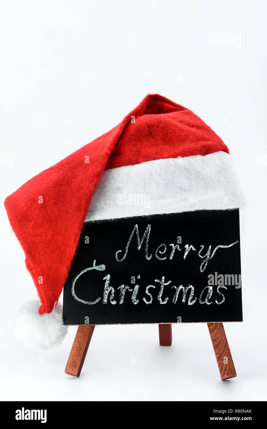 Eine Tafel mit dem Text: "Frohe Weihnachten!" in die Kreide mit einem Weihnachtsmann hat auf einem isolierten weißen Hintergrund geschrieben. Stockfoto