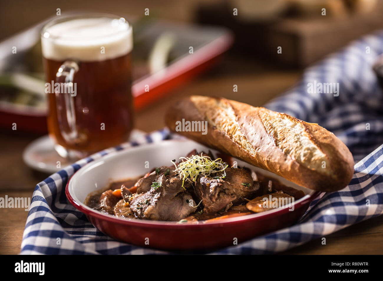 Gebratenes Wildschwein mit Karotten Pilze, Baguette und Bier vom Fass. Stockfoto