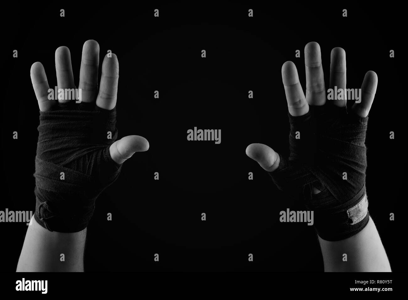 Zwei auferweckt Handflächen ein Mann in einem schwarzen textile Bandage gewickelt, schwarze und weiße Toning Stockfoto