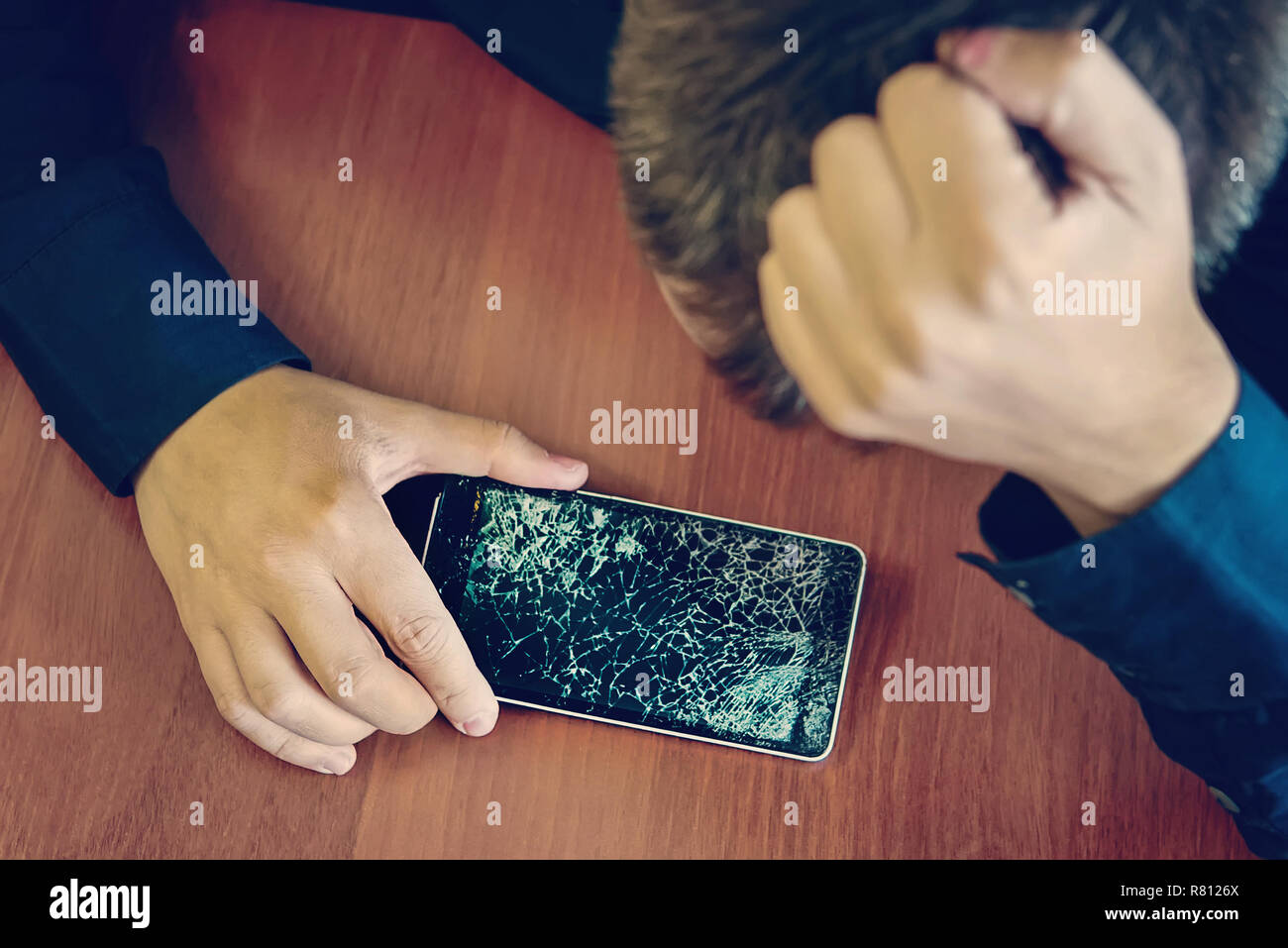 Verzweifelt und erstaunt Mann hält Smartphone geknackt. Bildschirm defekt Smartphone. Stockfoto