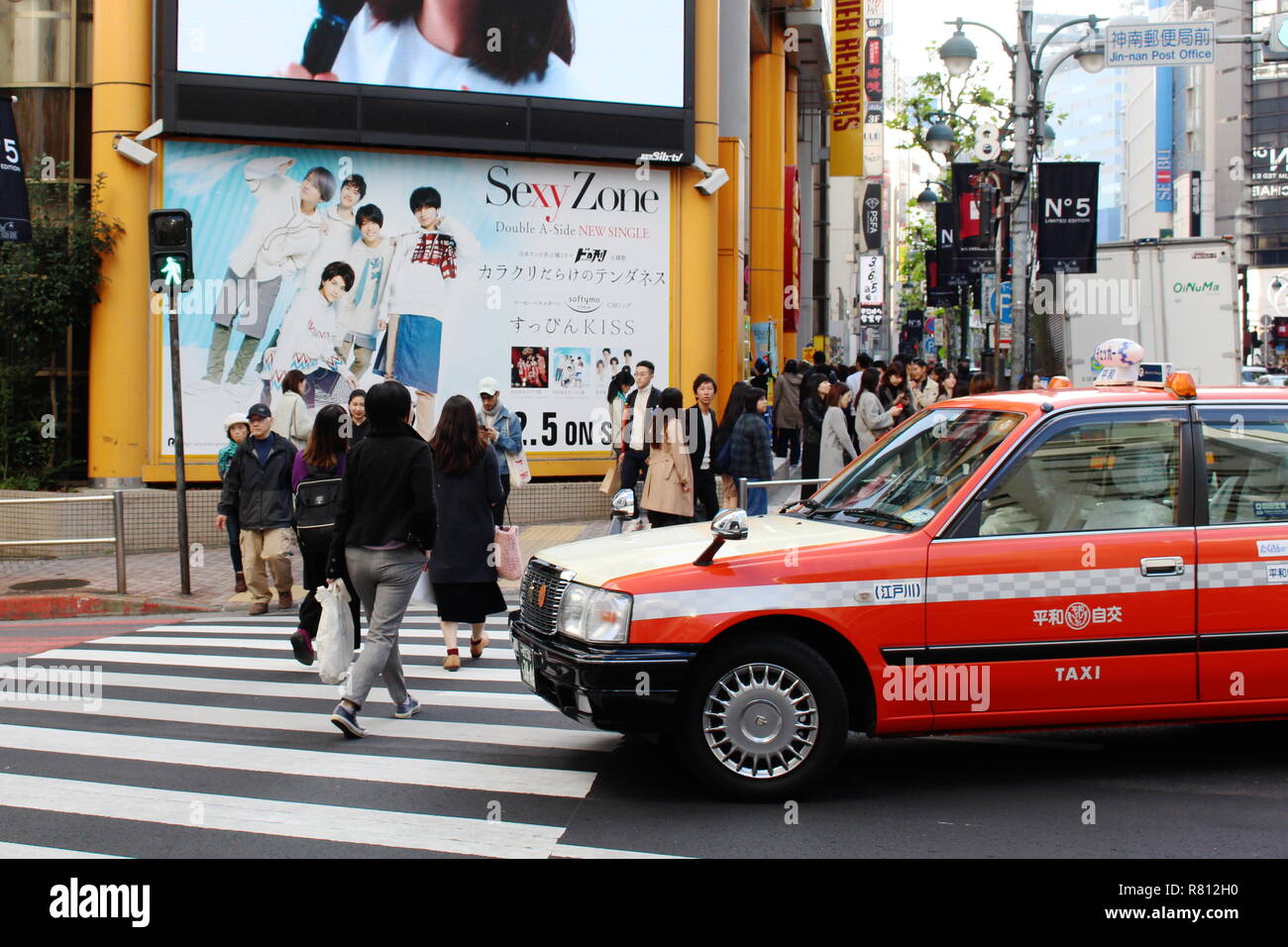 Ein Taxi wartet als fussgänger benutzen Sie eine Kreuzung vor der großen Shibuya Zweig der Tower Records. Stockfoto