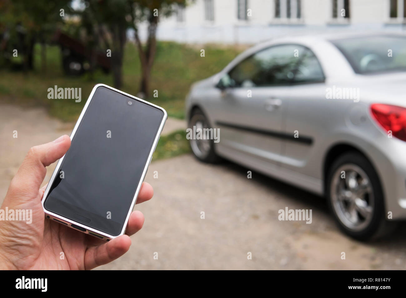 Handy Apps für Autobesitzer Konzept. Mann mit smart phone Status zu überprüfen, sein neues Auto steuern. Leer leer Mobiltelefon für Design. Stockfoto