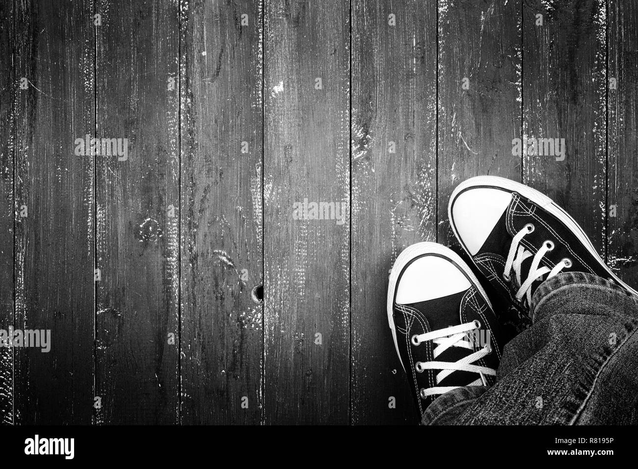 Bekleidung, Schuhe und Zubehör - Ansicht von oben Nahaufnahme Beine in Gumshoes und Jeans top Aussicht auf einer hölzernen Hintergrund einfarbig Stockfoto