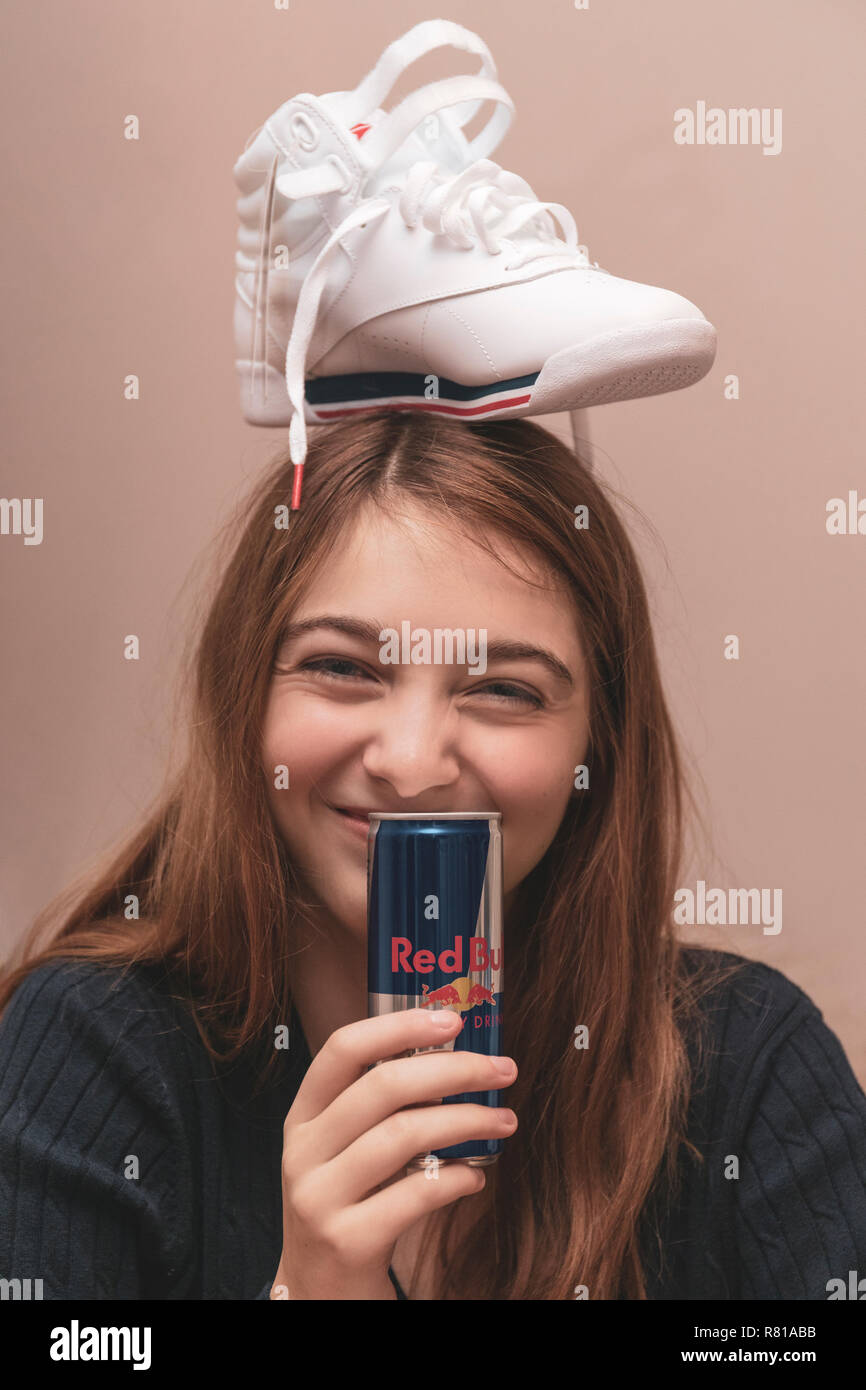 Gerne weibliche Teenager feiern Sie 16 Jahre, dumm mit brandneuer Sneaker auf Kopf und das Trinken aus einer Dose Red Bull Energy Drink. Stockfoto