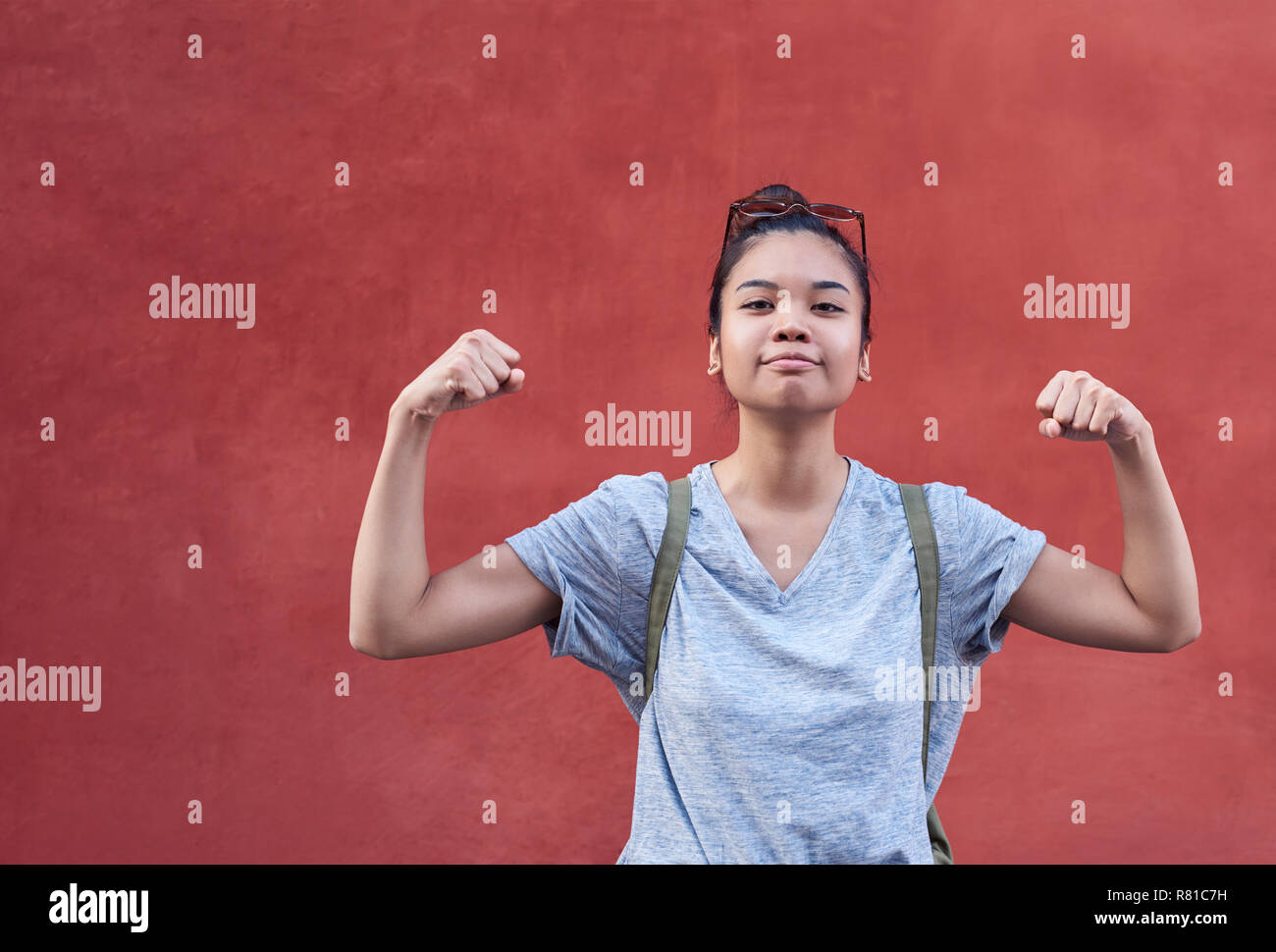 Lächelnde junge asiatische Frau scherzhaft ihre Muskeln außerhalb Biegen Stockfoto