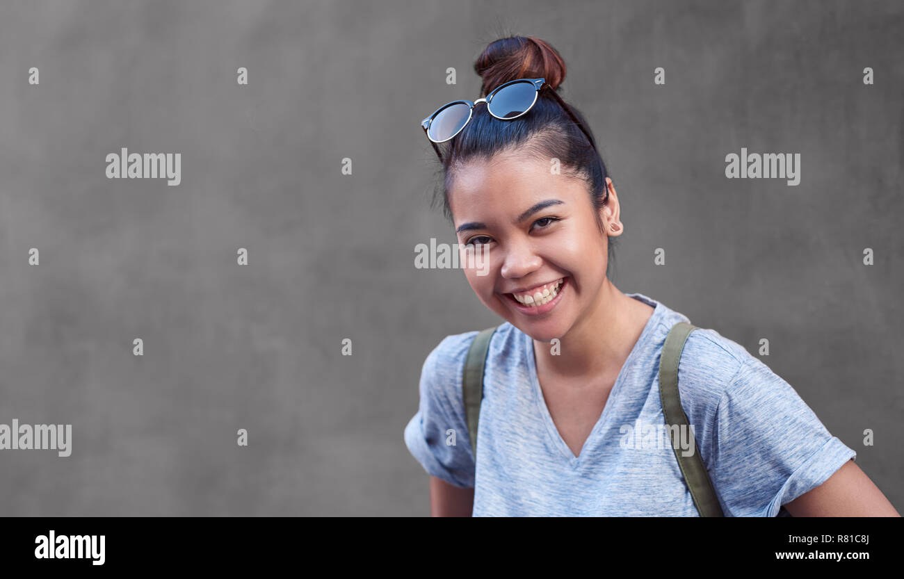 Freudige asiatische Frau vor einer Wand außerhalb Lachen Stockfoto