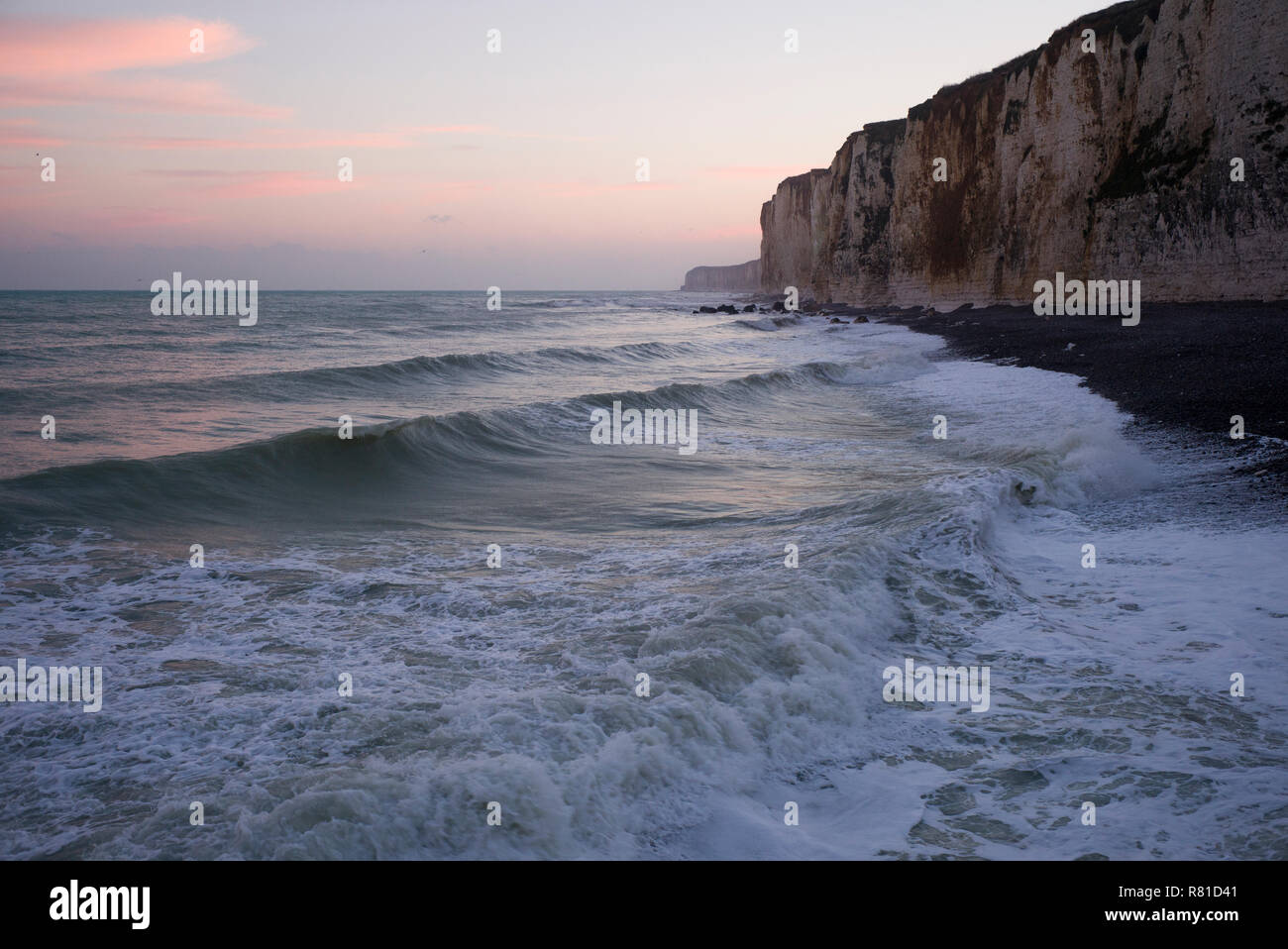 Wellen am Strand unter Felsen, Normandie, Frankreich Stockfoto