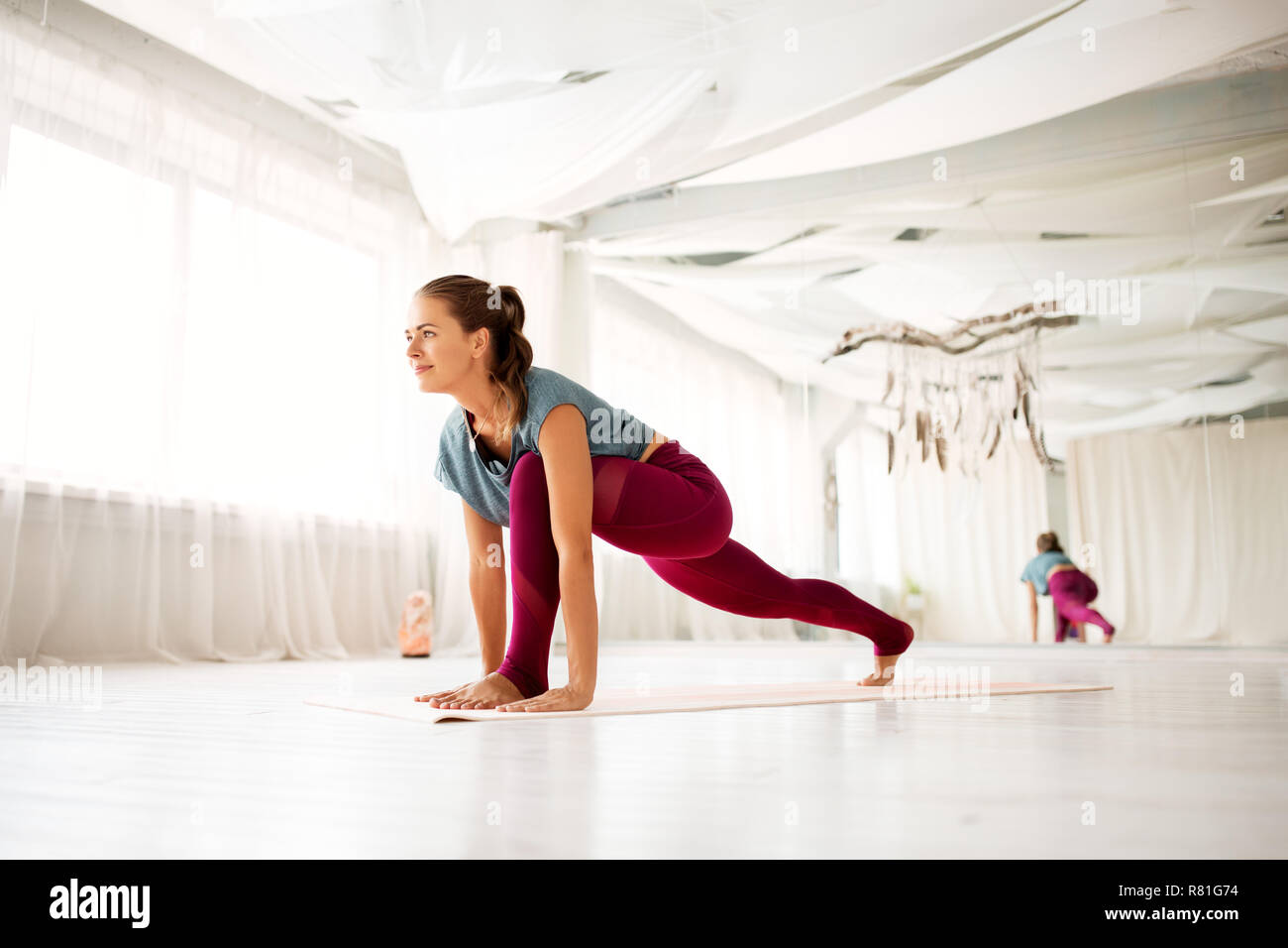 Frau, die hohe ausfallschritt Übung bei Yoga Studio Stockfoto