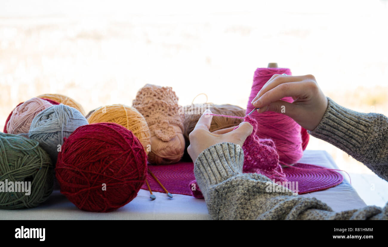 Eine Mutter strickt ein rosa Kleid aus Wolle für ihre Tochter es auf Weihnachten zu präsentieren. Handgefertigte Kleidung mit Liebe gemacht Stockfoto