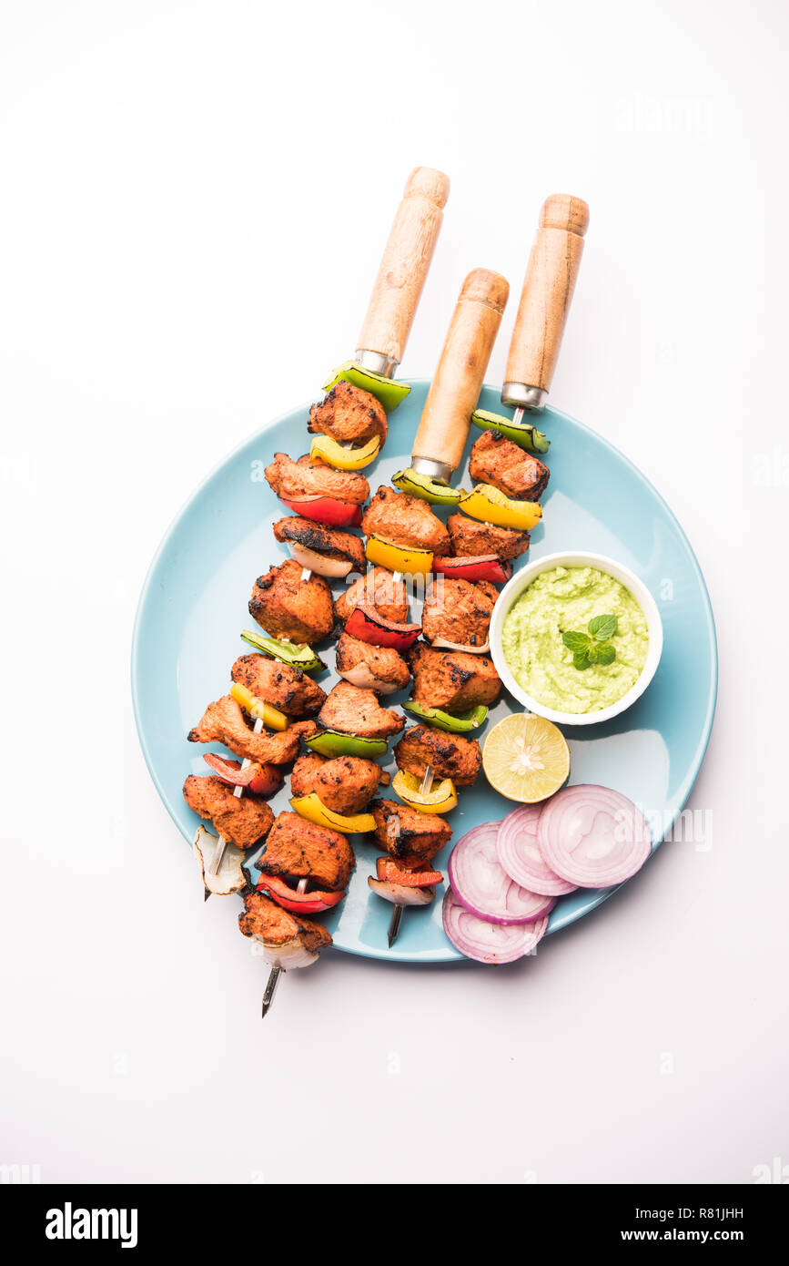 Chicken Tikka/skew Kebab. Traditionelle indische Gericht gekocht auf Holzkohle und Flamme, gewürzt & bunt garniert. Mit grüner Chutney und Salat serviert. Stockfoto