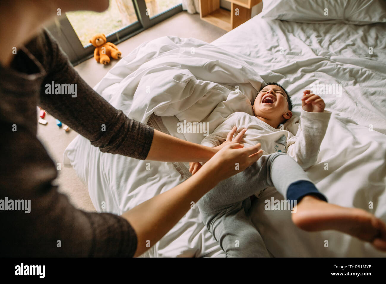 Mutter und Sohn gemeinsam spielen auf dem Bett zu Hause. Frau kitzeln kleine Junge im Bett. Stockfoto