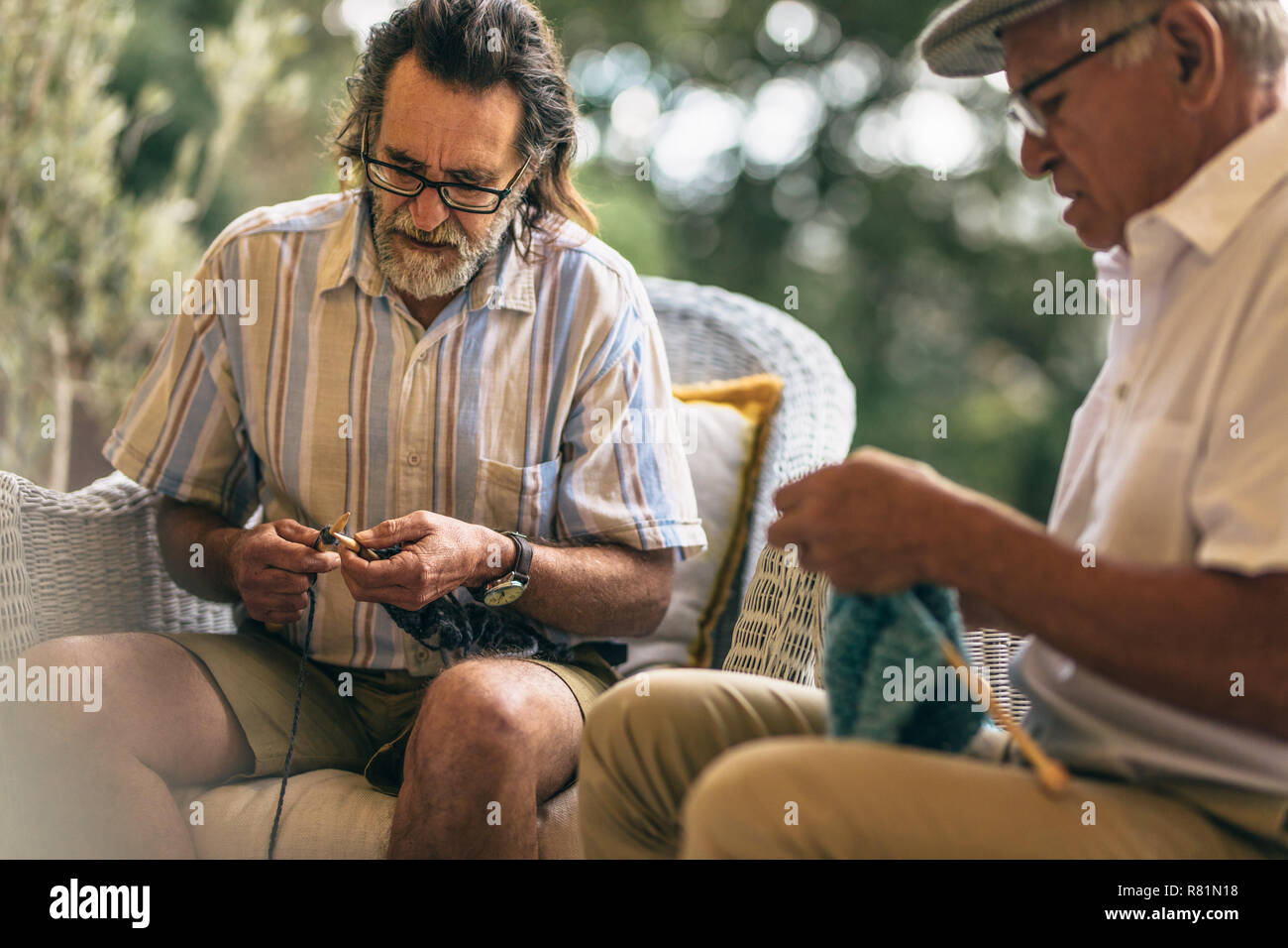 Zwei ältere Männer stricken lernen im Alter. Pensionierte männliche Freunde Stricken zum Zeitvertreib zu Hause. Stockfoto