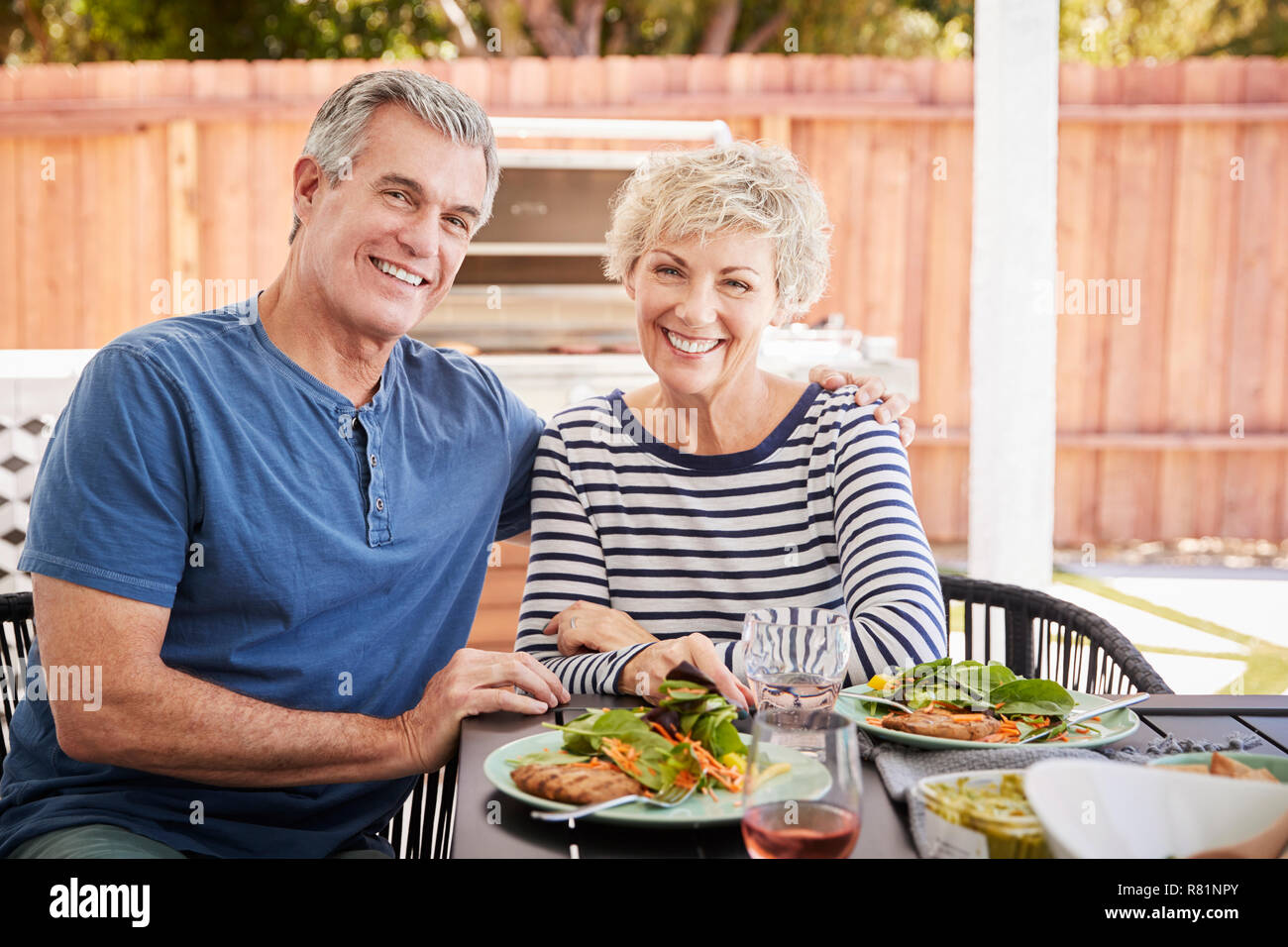 Senior weiß Paar sitzen beim Mittagessen im Garten mit Blick auf die Kamera Stockfoto