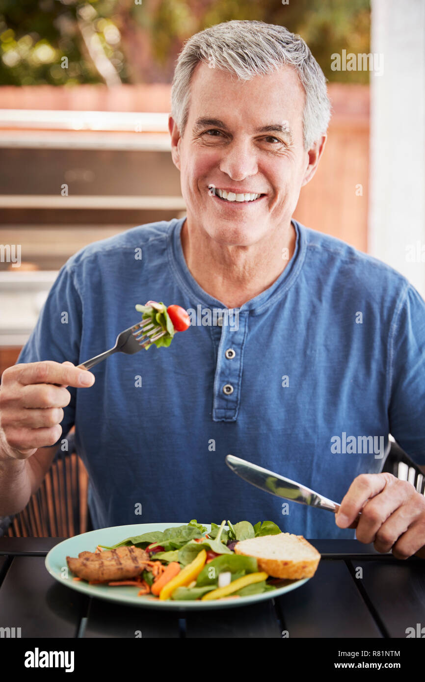 Senior weiß man das Mittagessen an einem Tisch draußen essen, vertikal Stockfoto