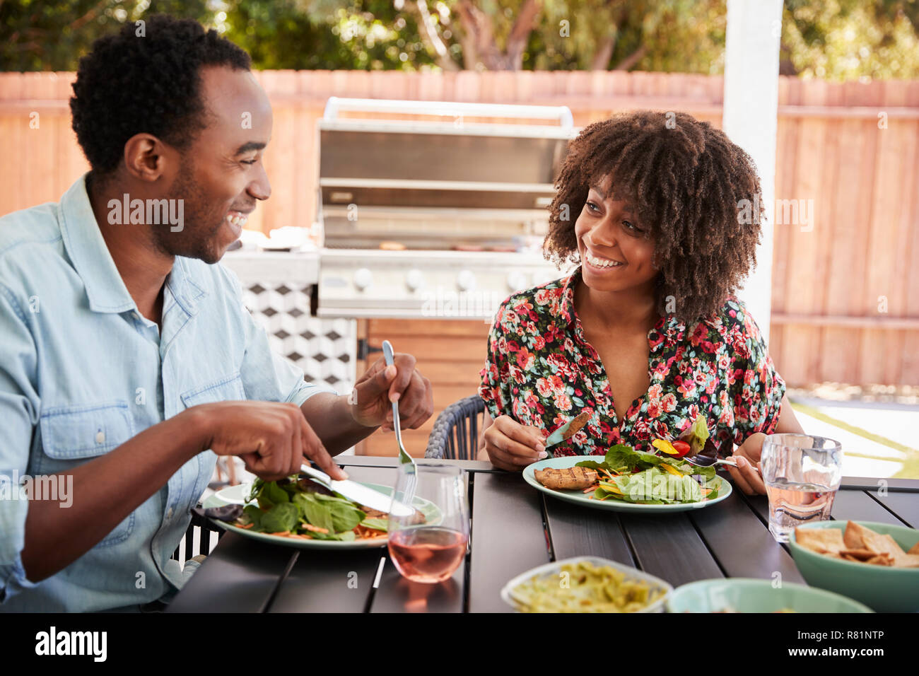 Junge schwarze Paar Essen an einem Tisch im Garten Stockfoto