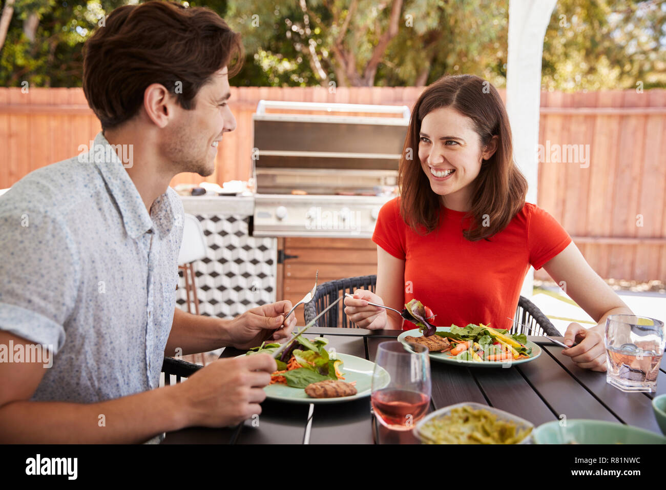 Junge weiße Paar Essen an einem Tisch im Garten Stockfoto