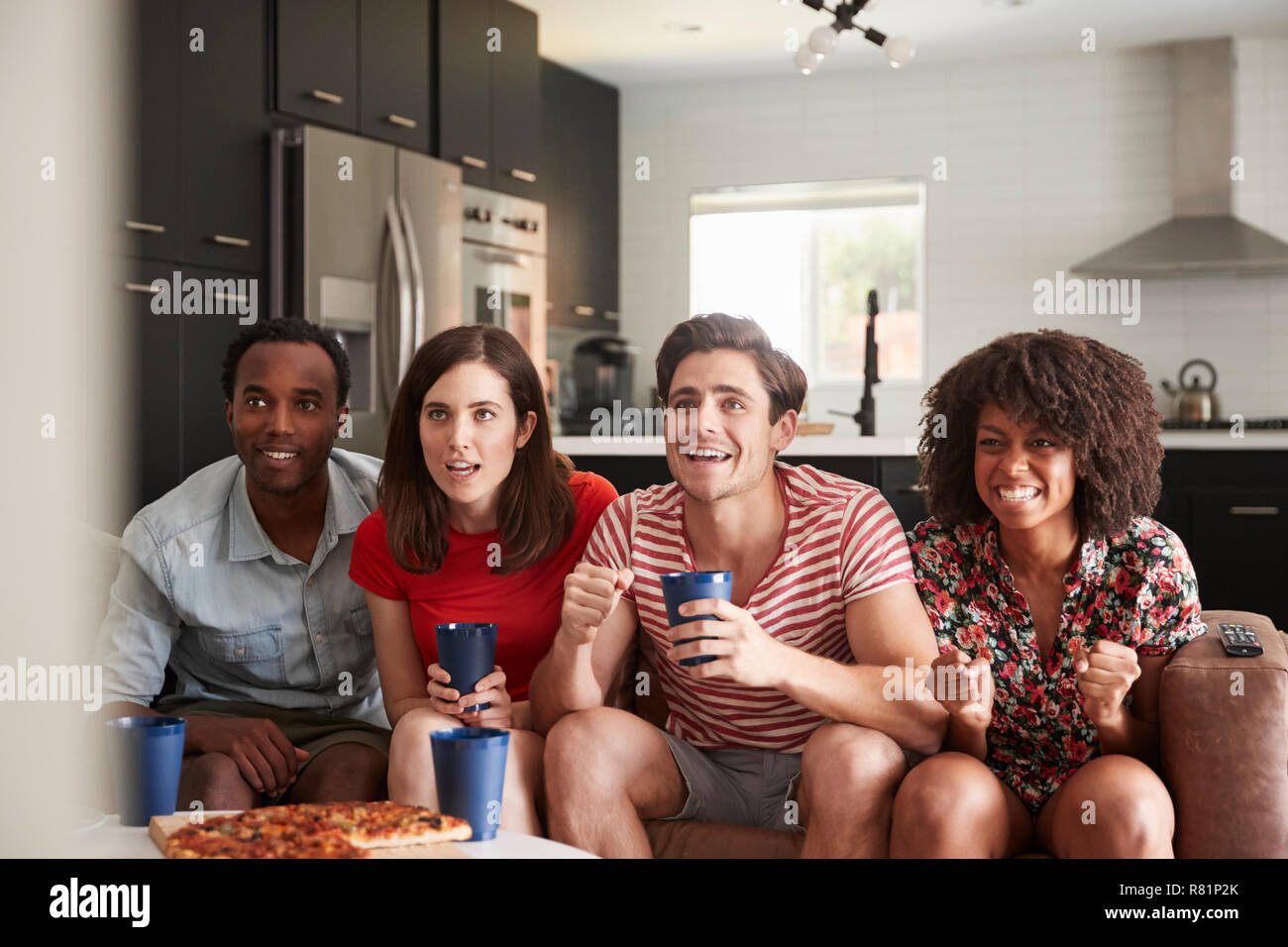 Vier junge erwachsene Freunde Sport im Fernsehen zu Hause Stockfoto
