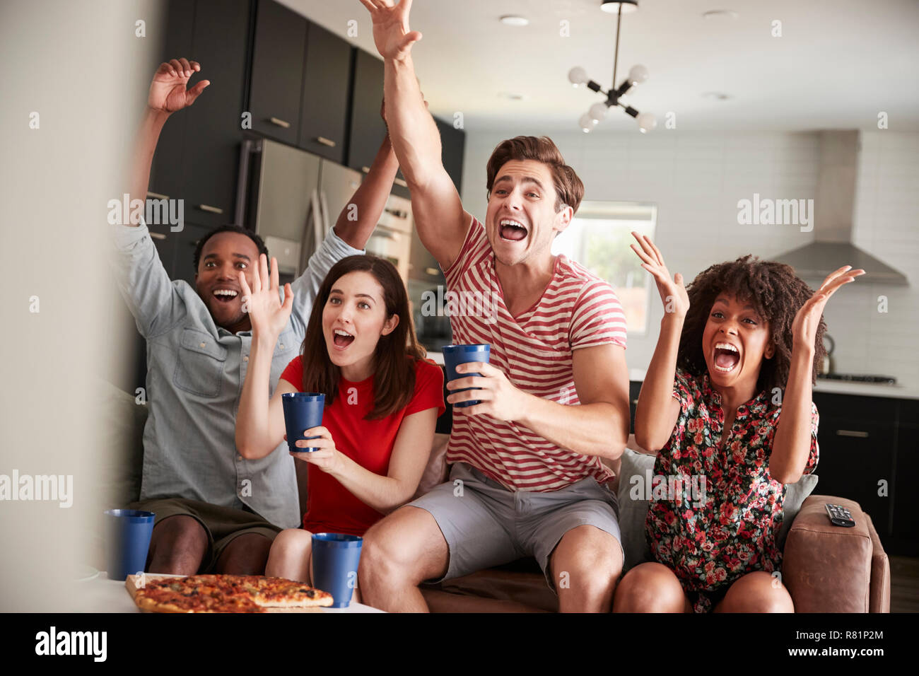 Vier junge erwachsene Freunde Sport im Fernsehen feiert Stockfoto