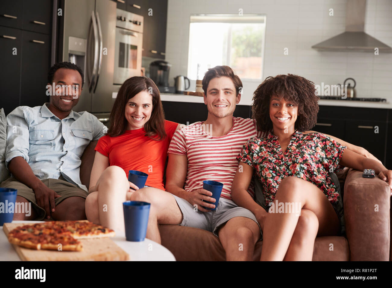 Vier junge erwachsene Freunde zusammen auf der Couch zu Hause Stockfoto