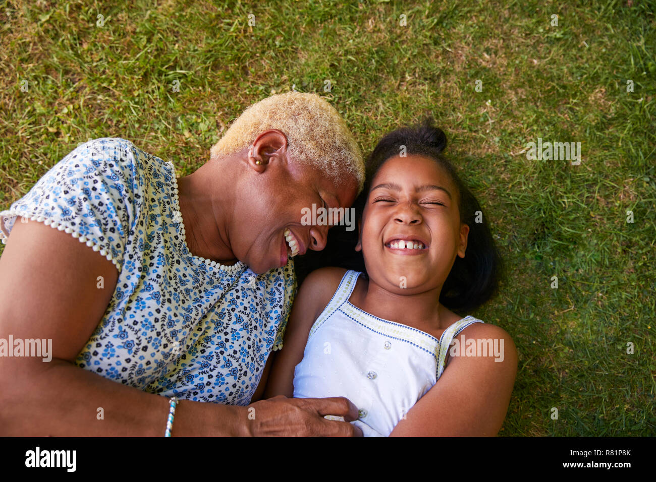 Schwarzes Mädchen und Großmutter liegen auf Gras, Overhead Nahaufnahme Stockfoto