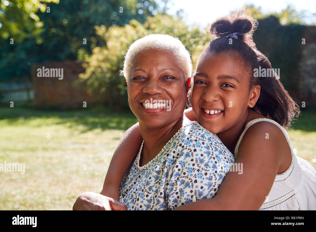 Ältere schwarze Frau und Enkelin sitzen, die außerhalb Stockfoto
