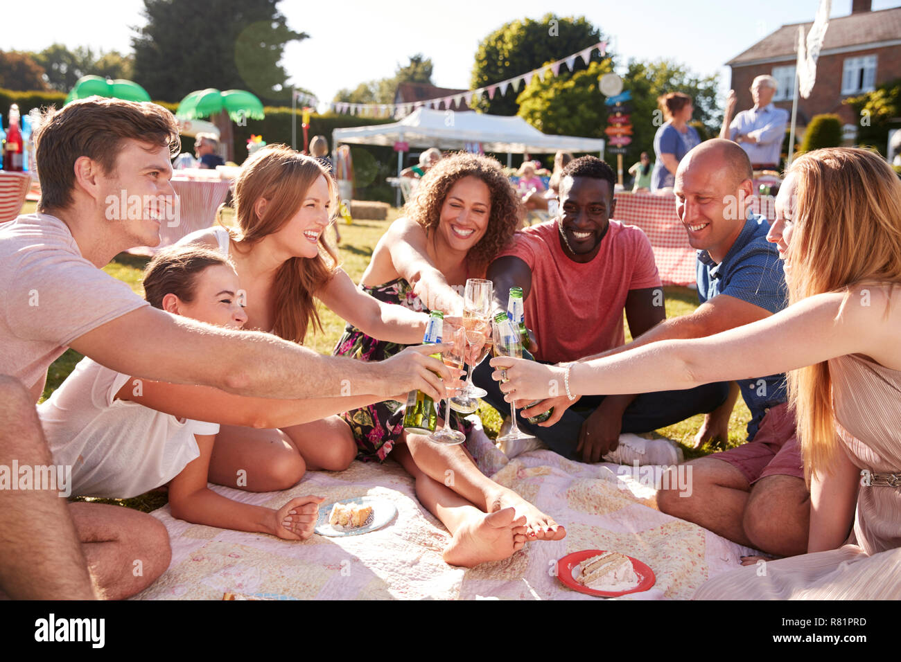Gruppe von Freunden sitzen auf Teppich bei Sommer Garten Fete und Toast Stockfoto