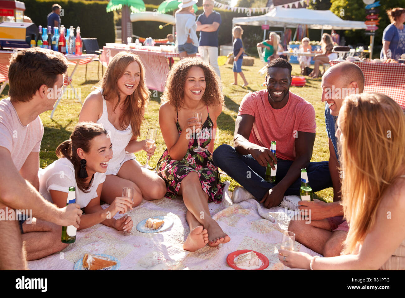 Gruppe von Freunden sitzen auf Teppich bei Sommer Garten Fete mit Getränken Stockfoto