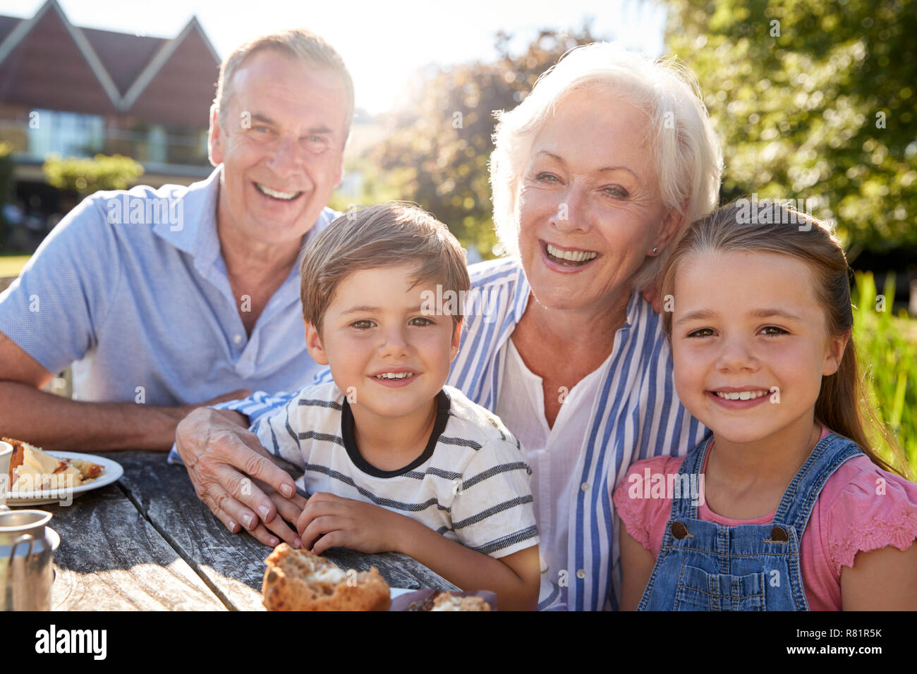 Portrait der Großeltern mit Enkeln genießen Sie im Sommer einen Snack im Cafe Stockfoto