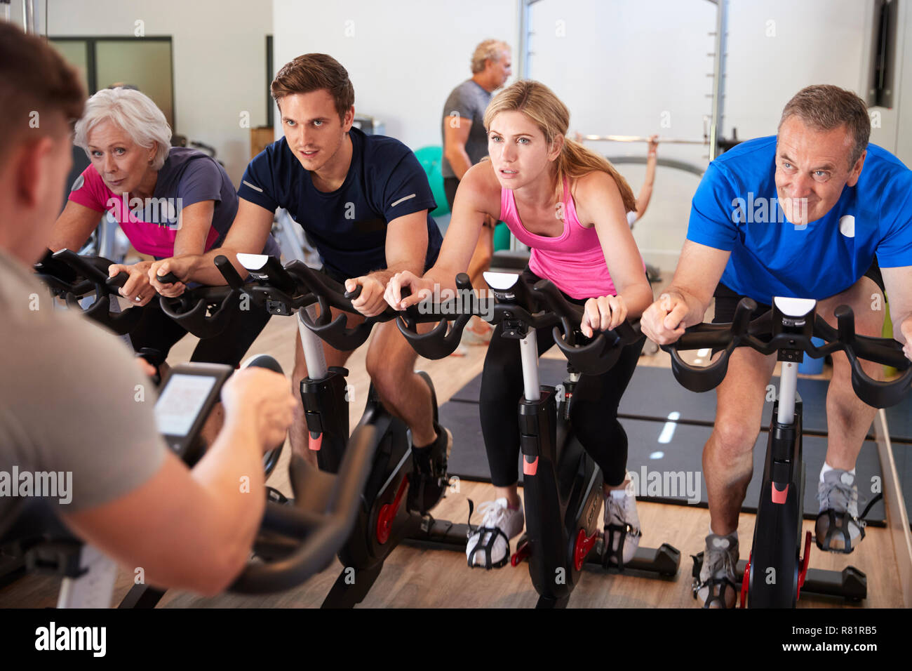 Männliche Trainer unter Spin Klasse In der Turnhalle Stockfoto