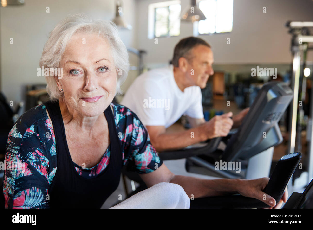Portrait von Active Senior Frau Ausruhen nach Ausübung auf Radfahren Maschinen in der Turnhalle Stockfoto