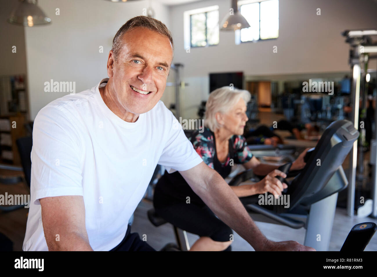 Portrait der aktiven älteren Menschen ruhen Nach dem Training auf dem Radfahren Maschinen in der Turnhalle Stockfoto