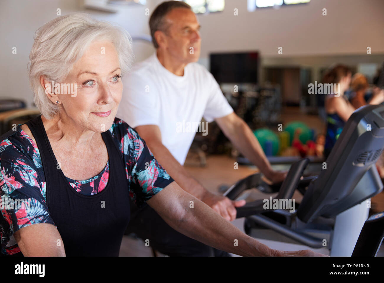 Active Senior Paar Ausübung auf Radfahren Maschinen in der Turnhalle Stockfoto
